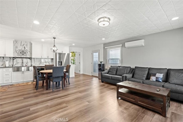 living room featuring recessed lighting, baseboards, light wood-style flooring, and a wall unit AC