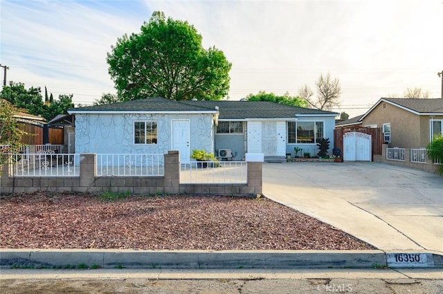 ranch-style house featuring a fenced front yard, concrete driveway, and a gate