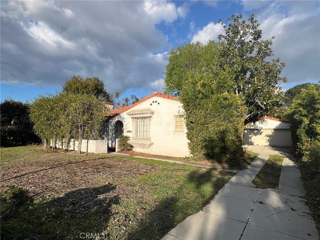 mediterranean / spanish-style house with a tile roof, fence, and stucco siding