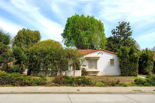 view of side of home with stucco siding and a tile roof