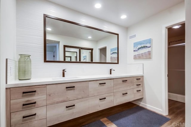 bathroom featuring double vanity, recessed lighting, wood finished floors, and a sink