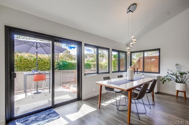 dining space with baseboards, a sunroom, wood finished floors, and vaulted ceiling