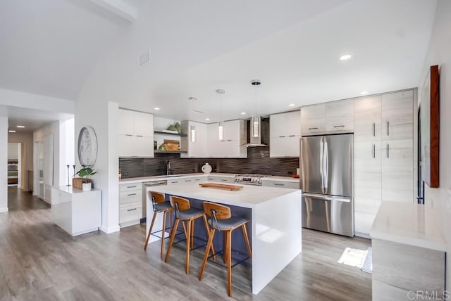 kitchen featuring modern cabinets, open shelves, a sink, stainless steel appliances, and wall chimney range hood