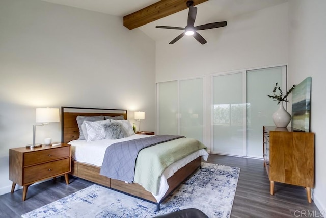 bedroom with beamed ceiling, two closets, high vaulted ceiling, wood finished floors, and ceiling fan