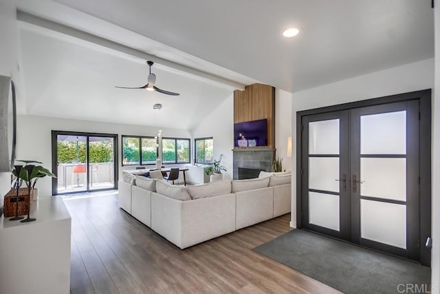 living room with lofted ceiling with beams, dark wood-style floors, ceiling fan, and a tile fireplace