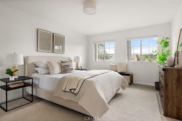 bedroom with light colored carpet and baseboards