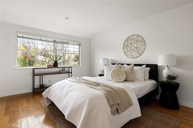 bedroom featuring vaulted ceiling, baseboards, and wood finished floors