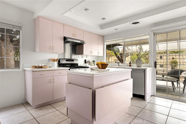 kitchen with visible vents, a tray ceiling, light countertops, under cabinet range hood, and gas range