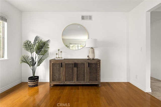 interior space with plenty of natural light, wood finished floors, and visible vents