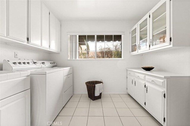 clothes washing area with light tile patterned floors, cabinet space, and washer and dryer