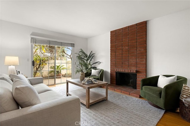 living room featuring a brick fireplace and wood finished floors