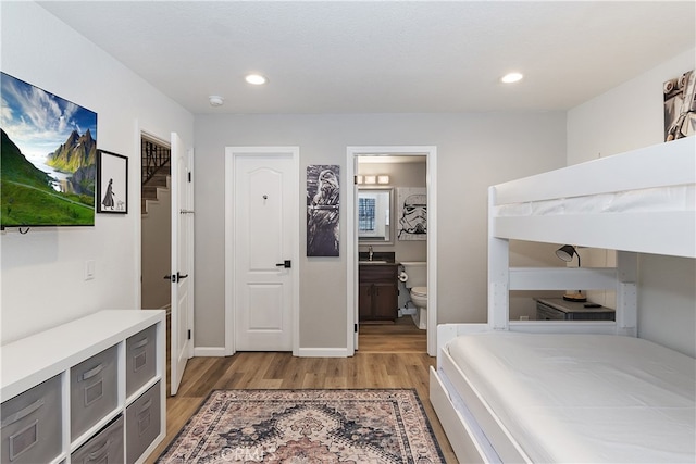 bedroom featuring recessed lighting, a sink, light wood-style flooring, and baseboards