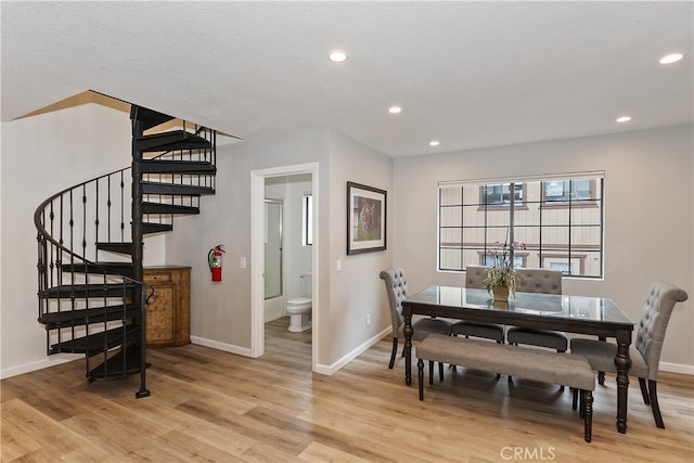 dining room with a textured ceiling, light wood-style flooring, recessed lighting, baseboards, and stairway