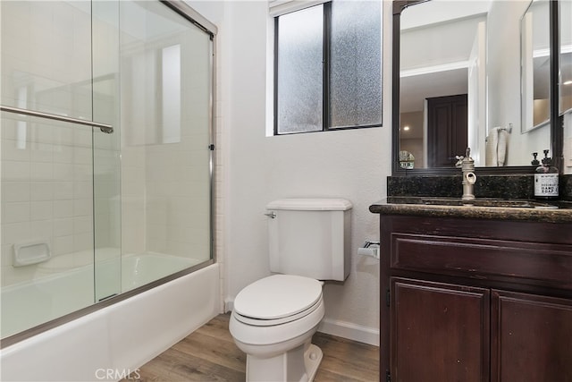 full bath featuring vanity, bath / shower combo with glass door, wood finished floors, and toilet