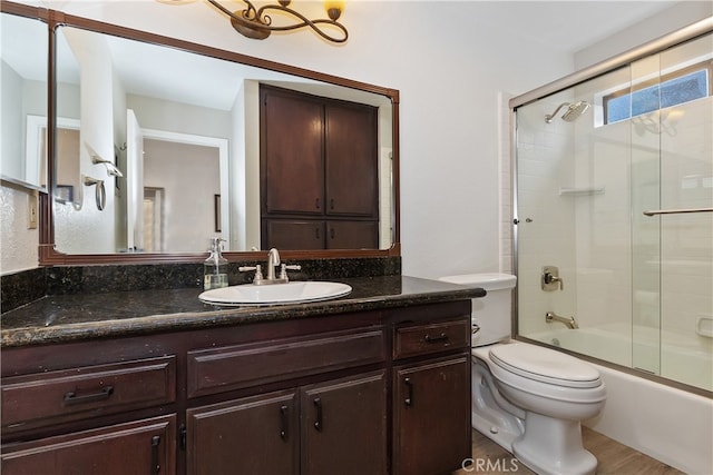 full bath featuring toilet, shower / bath combination with glass door, and vanity