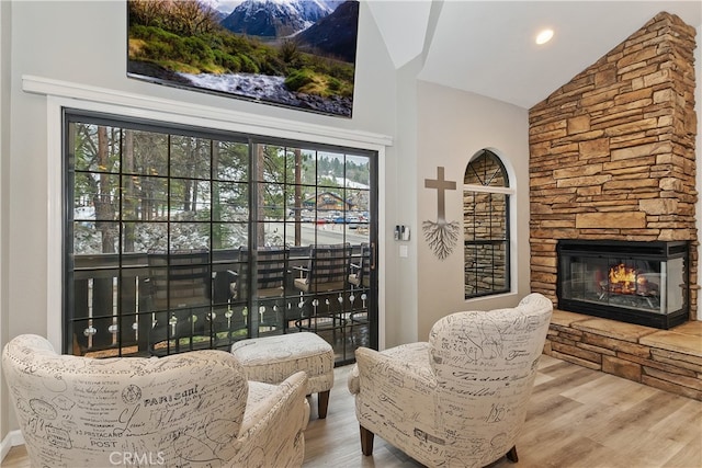 sitting room with lofted ceiling, a fireplace, and wood finished floors