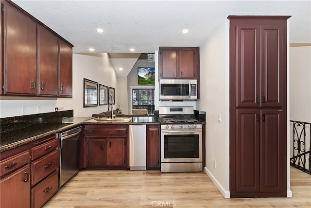 kitchen with appliances with stainless steel finishes, a textured ceiling, light wood-style floors, a sink, and recessed lighting