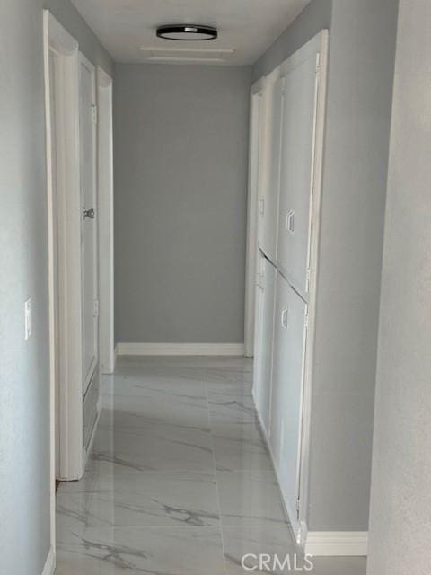 corridor featuring marble finish floor and baseboards