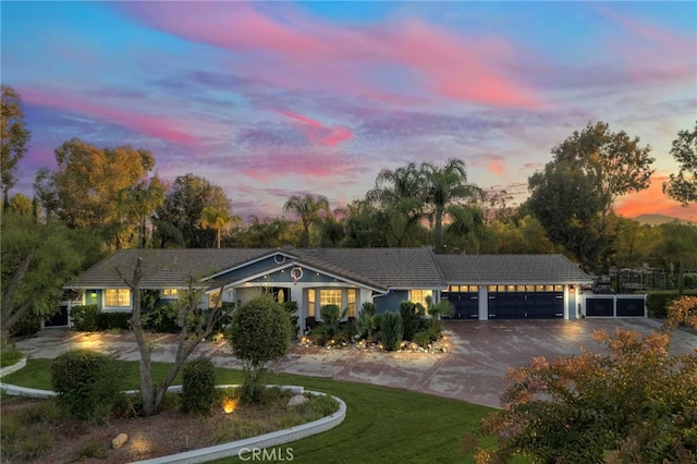 single story home with a front yard, an attached garage, a tile roof, and driveway