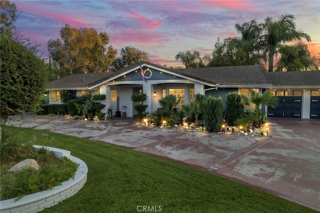 ranch-style house with a garage, concrete driveway, and a yard