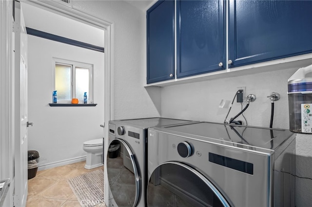 laundry area with washer and clothes dryer, light tile patterned floors, cabinet space, and baseboards