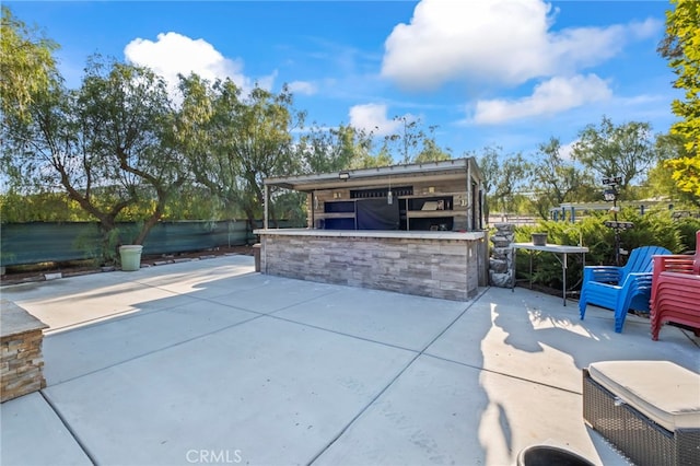 view of patio with outdoor dry bar and fence