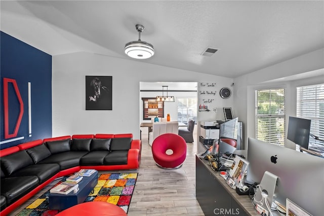 living area featuring a healthy amount of sunlight, lofted ceiling, and wood finished floors