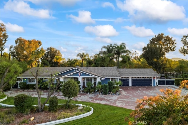 ranch-style home featuring a front lawn, a tiled roof, an attached garage, and driveway