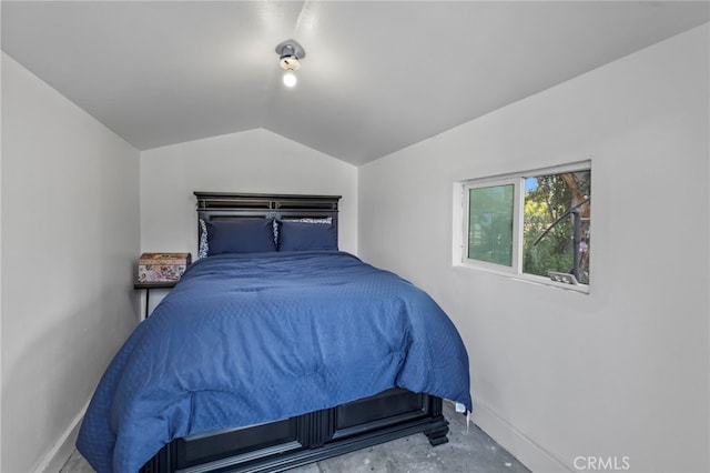 bedroom with baseboards, unfinished concrete floors, and vaulted ceiling