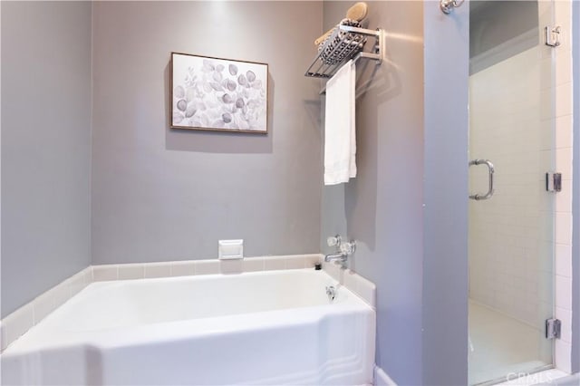 bathroom featuring a shower stall and a bath