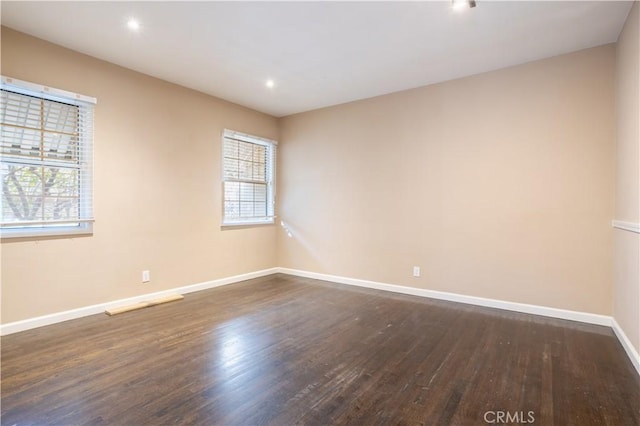 unfurnished room featuring dark wood-style floors, baseboards, a wealth of natural light, and recessed lighting