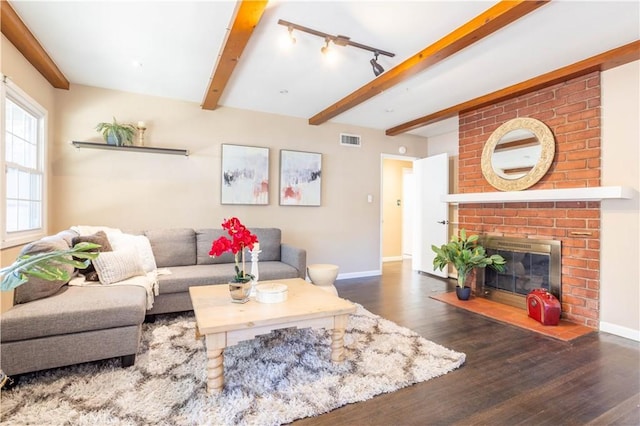 living area with baseboards, visible vents, wood finished floors, a fireplace, and beam ceiling