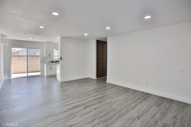 unfurnished living room with recessed lighting, baseboards, and wood finished floors