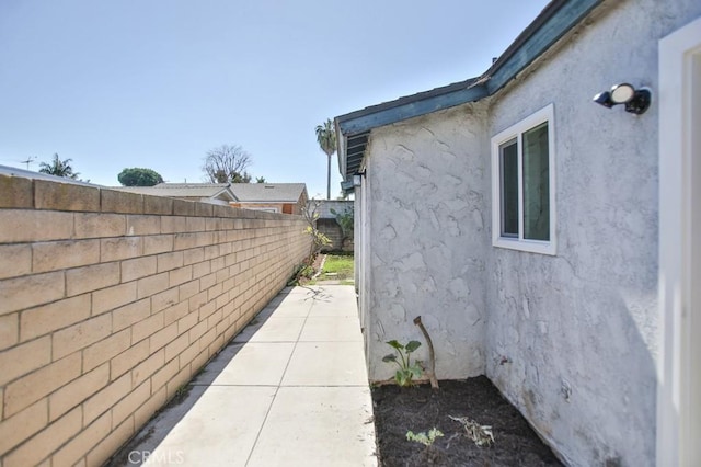 view of side of property featuring fence and stucco siding