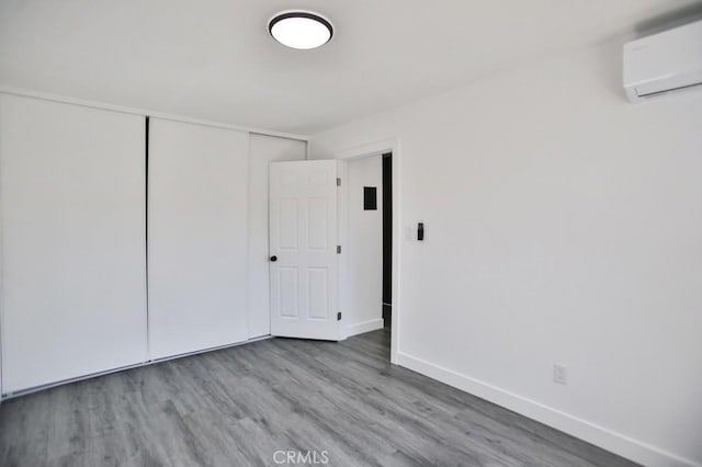 empty room with baseboards, a wall unit AC, and wood finished floors