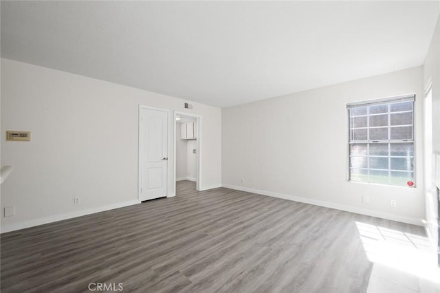 unfurnished room with visible vents, baseboards, and wood finished floors