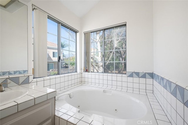 full bathroom featuring vaulted ceiling, vanity, and a whirlpool tub