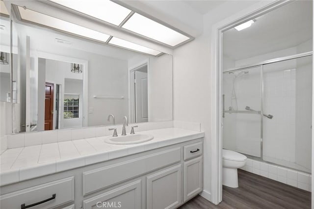 full bath with toilet, a shower stall, visible vents, and wood finished floors