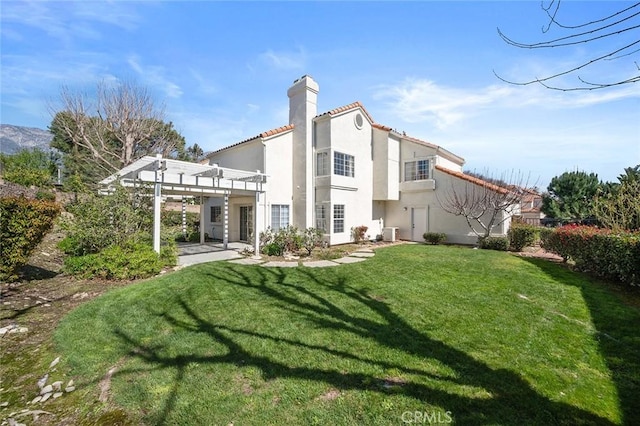 back of property featuring a chimney, a yard, a patio area, a pergola, and stucco siding