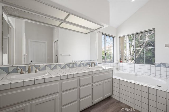 full bathroom with lofted ceiling, double vanity, a sink, and a bath