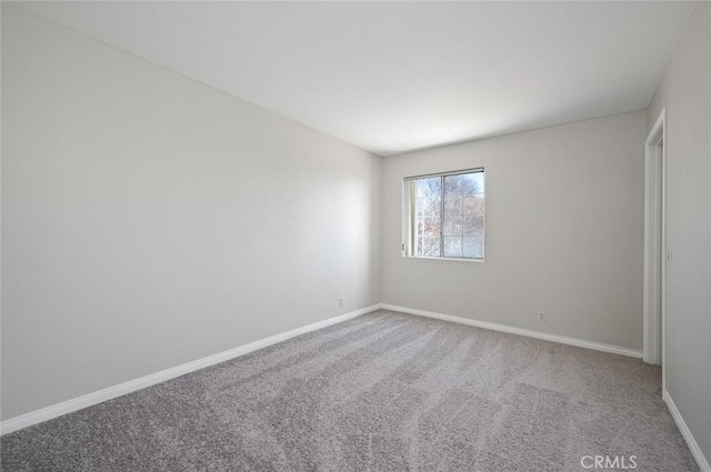 spare room featuring carpet floors and baseboards