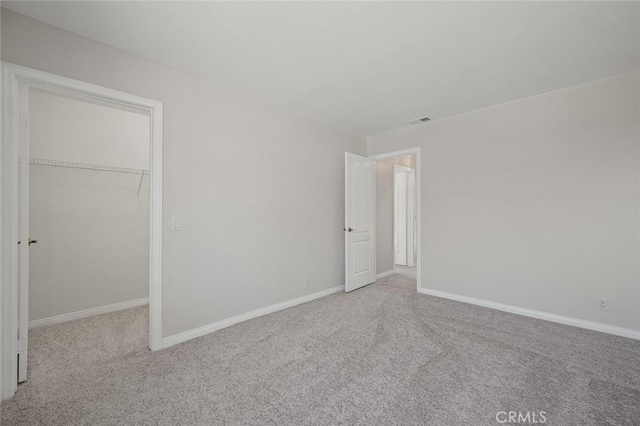 unfurnished bedroom with visible vents, baseboards, a spacious closet, a closet, and carpet