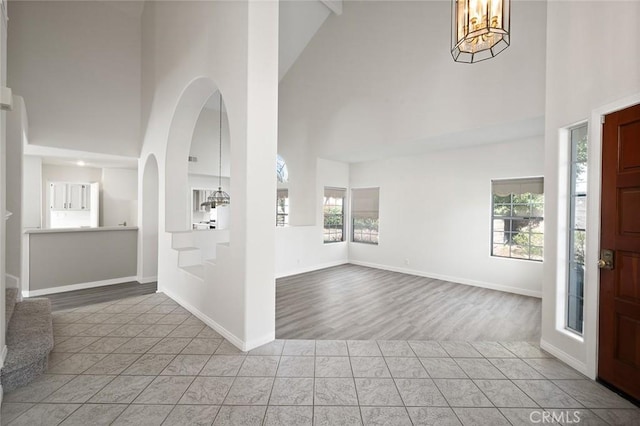 entryway with baseboards, a notable chandelier, a high ceiling, and light tile patterned floors