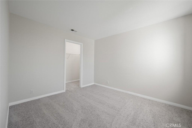 empty room with carpet floors, visible vents, and baseboards