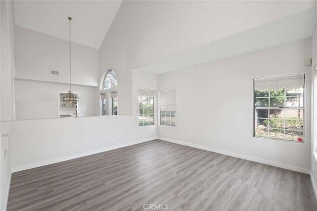 unfurnished room with high vaulted ceiling, baseboards, and wood finished floors