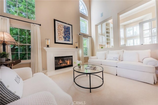 living area featuring a glass covered fireplace, a high ceiling, and visible vents