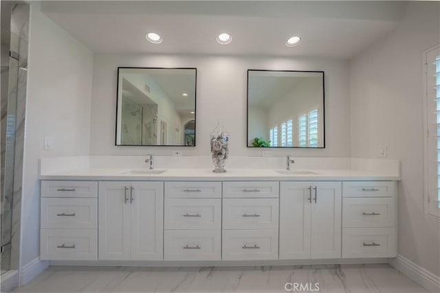 bathroom with double vanity, a shower stall, and a sink