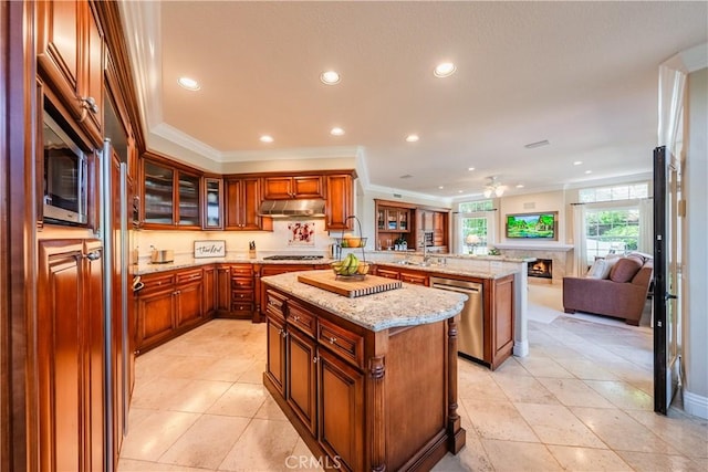 kitchen featuring a kitchen island, a peninsula, under cabinet range hood, appliances with stainless steel finishes, and open floor plan