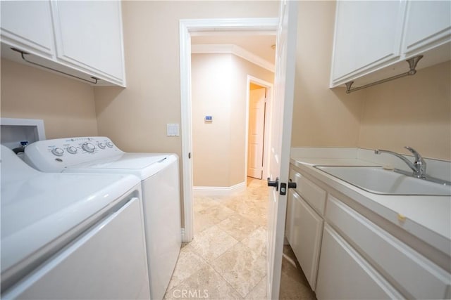 washroom featuring washing machine and dryer, cabinet space, baseboards, and a sink