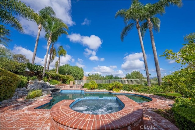 view of swimming pool with an in ground hot tub and fence